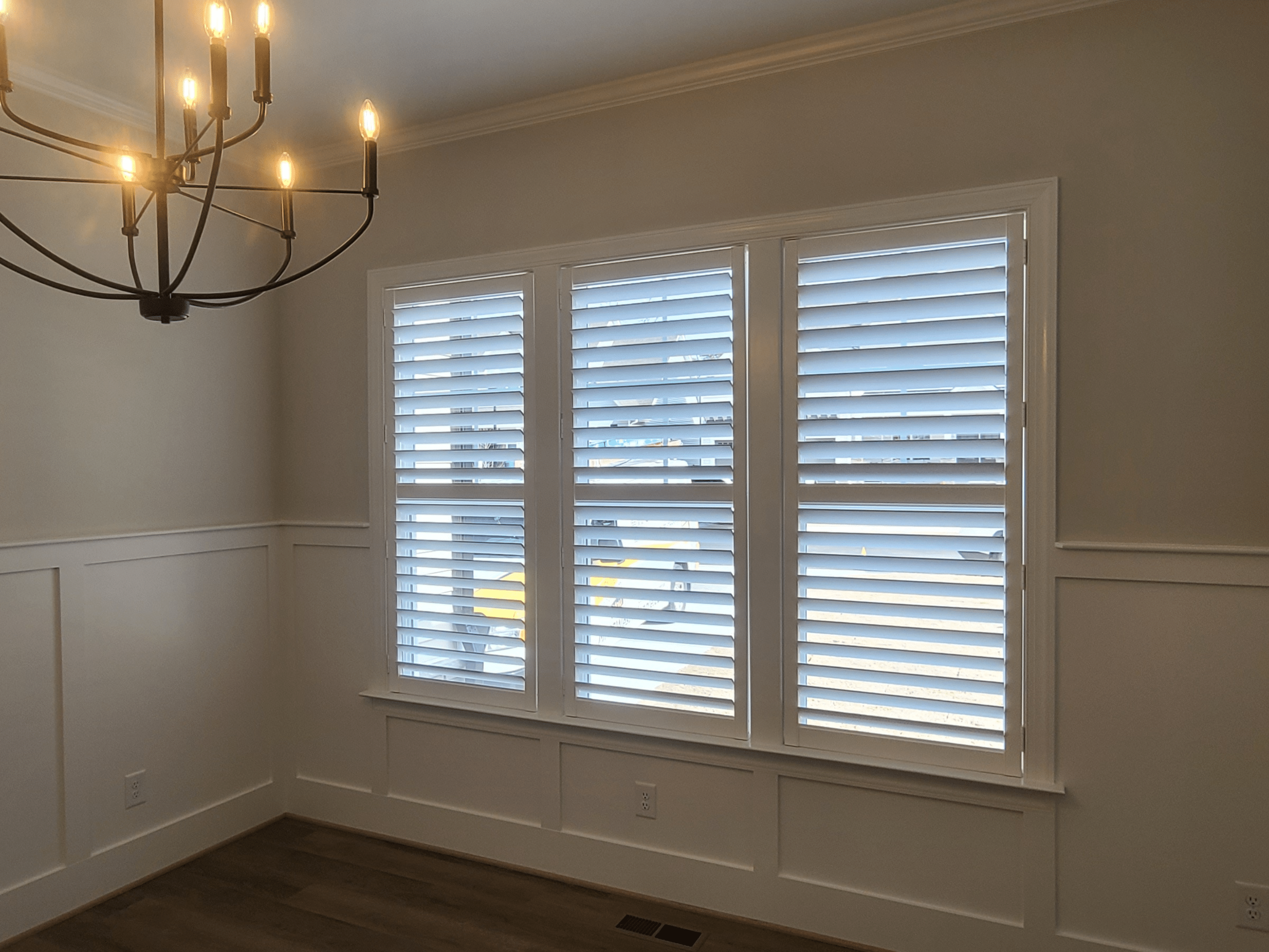 Newly installed shutters in a dining room with a hanging chandelier